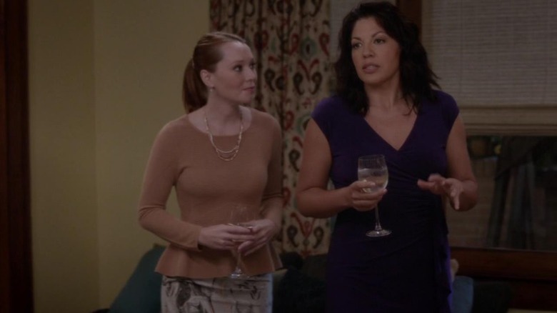 Samantha Sloyan as Dr. Penny Blake and Sara Ramirez as Dr. Callie Torres standing side by side and holding wine glasses on Grey's Anatomy