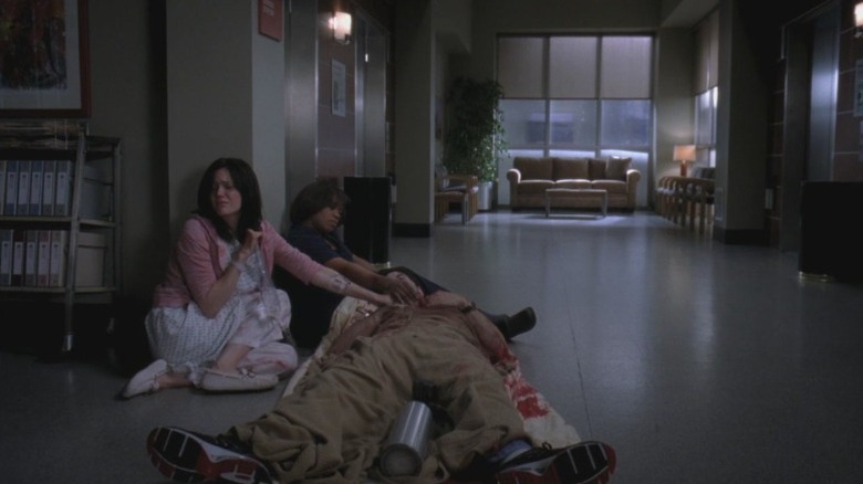 Chandra Wilson as Dr. Miranda Bailey sitting on a corridor floor next to Mandy Moore as Mary Portman and cradling Robert Baker as a dying Dr. Charles Percy on Grey's Anatomy