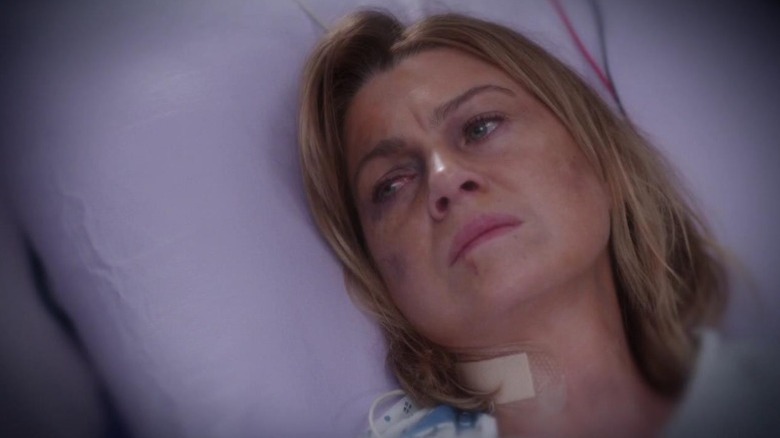 Ellen Pompeo as Dr. Meredith Grey lying on a hospital bed with bruises on her face and neck on Grey's Anatomy