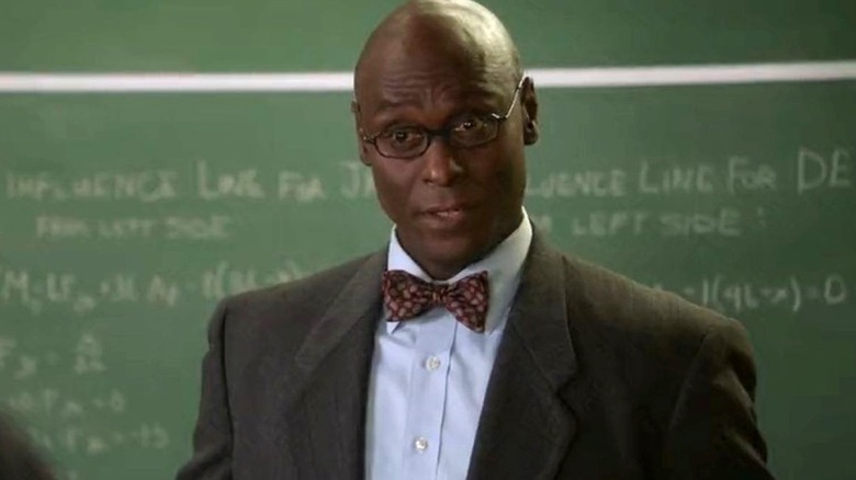 Lance Reddick as Professor Boucher stands in front of a chalkboard on Young Sheldon