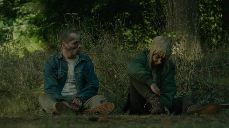 Pat (Anton Yelchin) sitting next to Amber (Imogen Poots) in the woods in Green Room