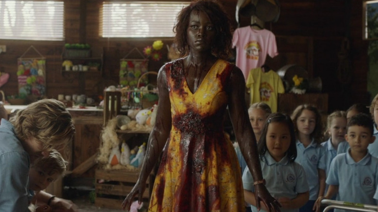 Lupita Nyong'o as Caroline covered in blood, standing in front of her young students in Little Monsters