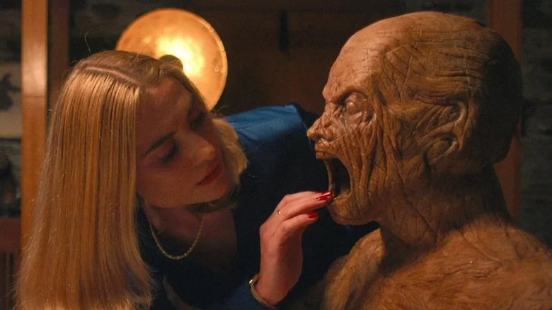 Caroline Menton as Yana, risking a digit as she touches a creepy wooden sculpture of a monster in Oddity