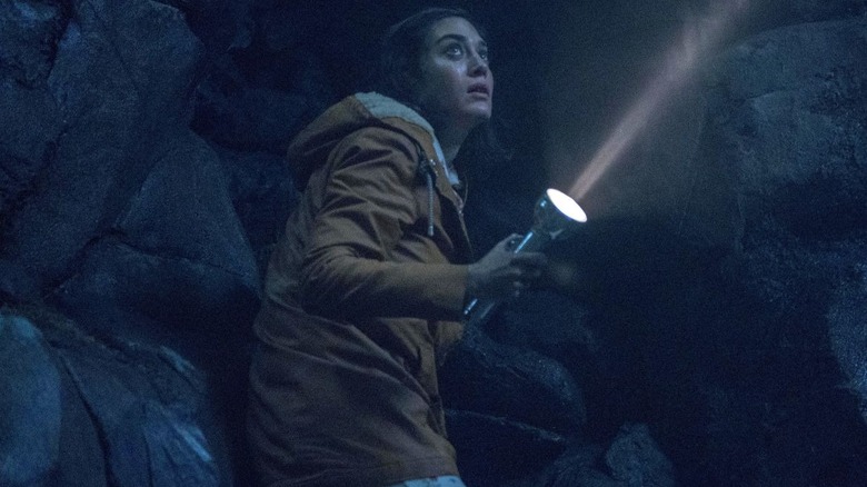 Lizzy Caplan as Annie shines a flashlight while walking in a cave on Castle Rock