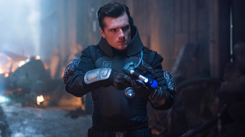 Josh Hutcherson as Josh Futturman in a futuristic wardrobe holding a high-tech weapon in a cluttered alley in Future Man