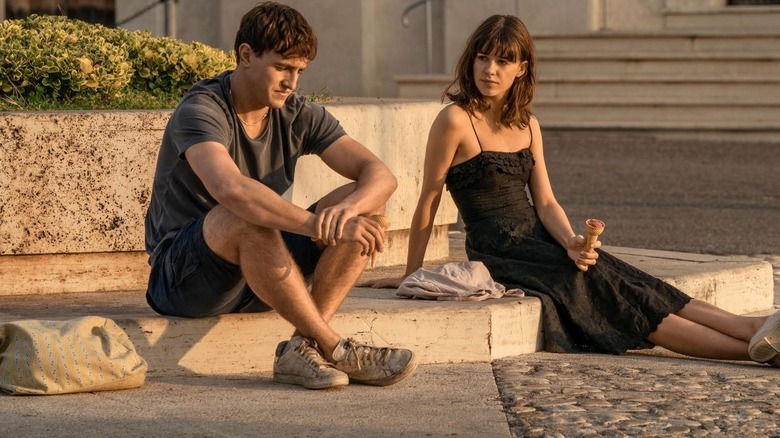 Paul Mescal as Connell sits on the sidewalk next to Daisy Edgar-Jones as Marianne on Normal People
