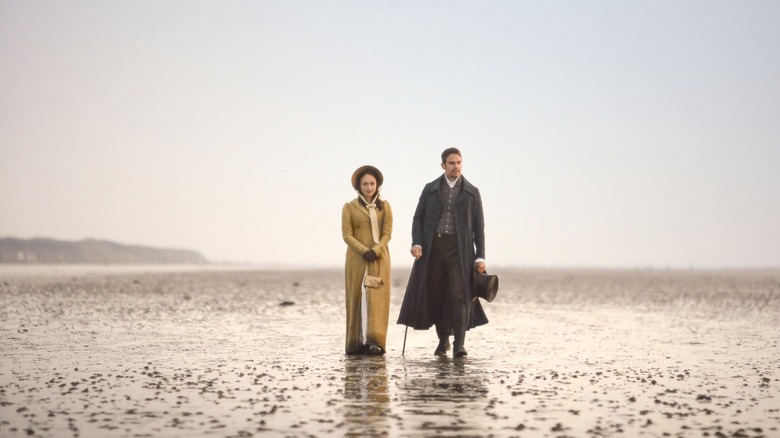 Rose Williams and Theo James in "Sanditon" walk on beach