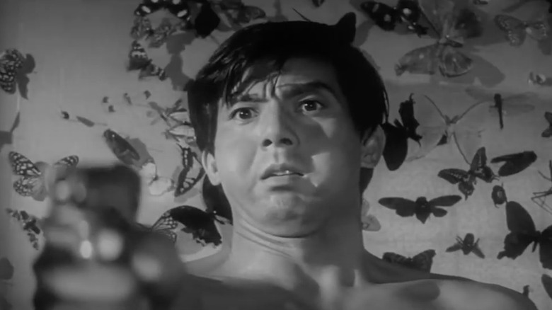 Jō Shishido standing in front of butterflies, pointing gun