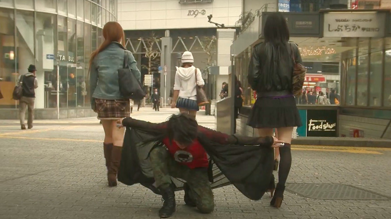 Takahiro Nishijima kneeling in front of two women