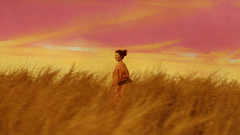 Yuki (Keiko Kishi) walks through a grassy field under an orange and pink sky in Kwaidan