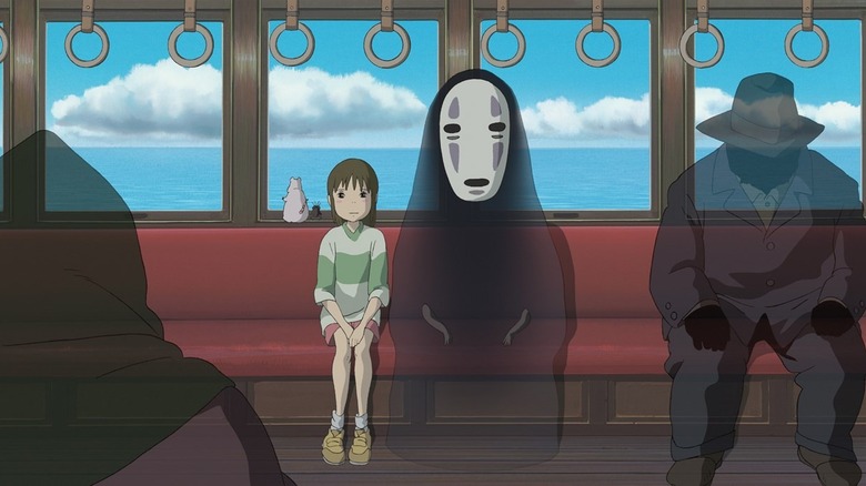 Chihiro sits on a ghostly train next to No-Face in Spirited Away