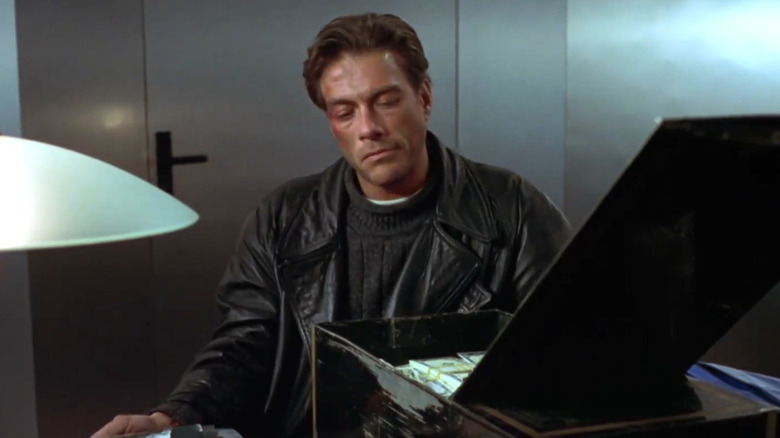 Jean-Claude Van Damme's Alain Moreau looking at money in Maximum Risk