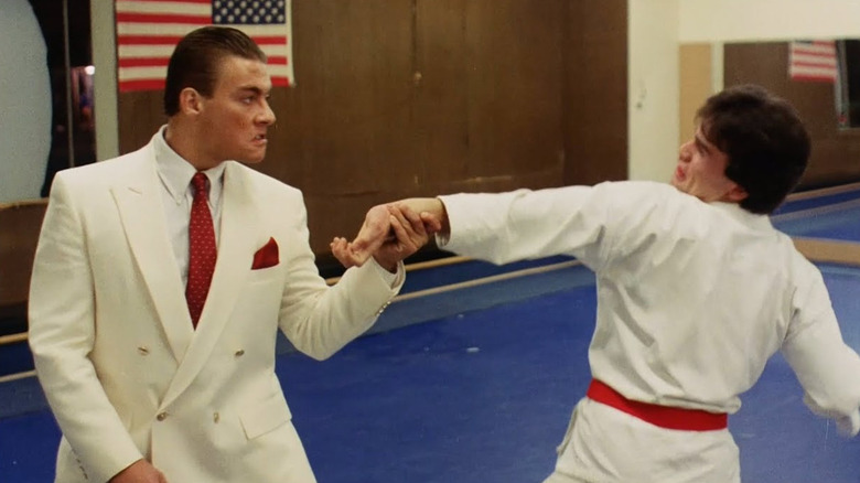 Jean-Claude Van Damme's Ivan "the Russian" Krachinsky sparring in a white suit with a karate student in No Retreat, No Surrender