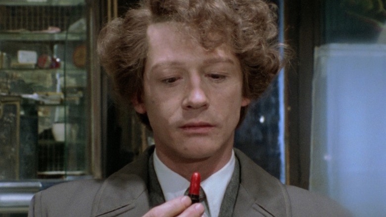 Young John Hurt looking at a lipstick