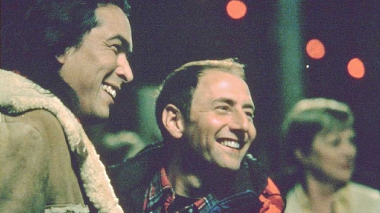 Two men smile at something