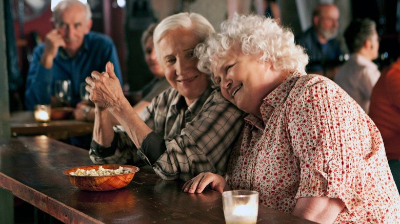 Two older women lean on each other