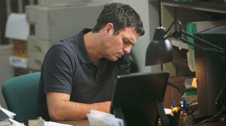 Michael Rezendes (Mark Ruffalo) sits at his desk with his eyes closed in Spotlight