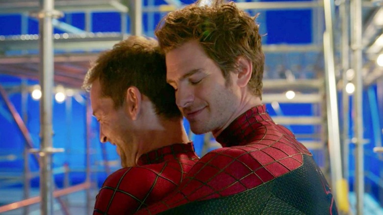 Andrew Garfield hugging Tobey Maguire from behind in their Spider-Man costumes