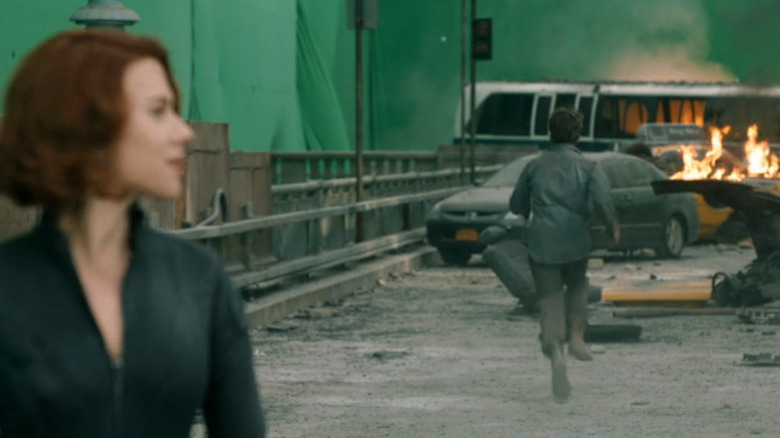 Scarlett Johansson as Natasha Romanoff staring ahead while Mark Ruffalo runs away towards a green screen