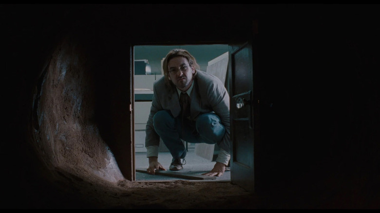 Craig (John Cusack) looks into a tiny door from an office in Being John Malkovich