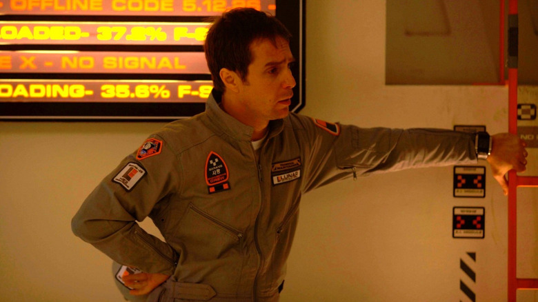 Sam (Sam Rockwell) bathed on orange light standing next to a ladder in Moon