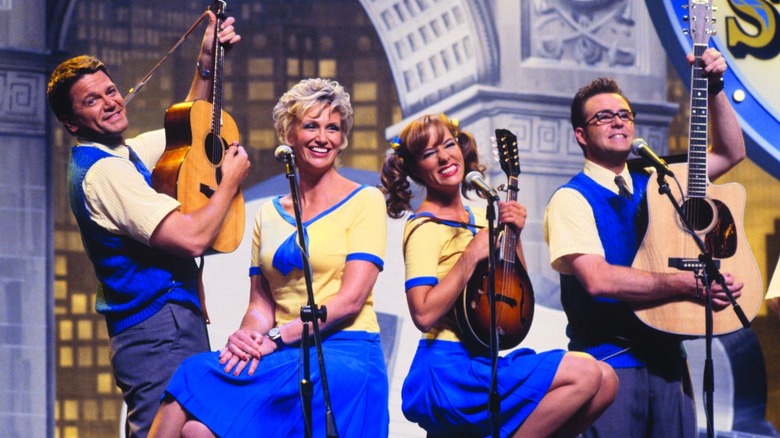 A folk band sits on stage performing in A Mighty Wind.
