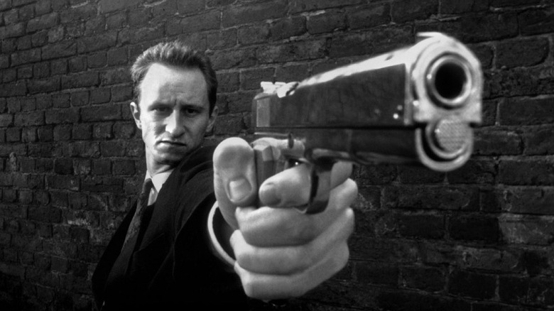 A man points a gun at the camera in Man Bites Dog.