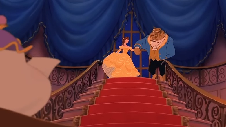 Mrs. Potts watches in the foreground as Belle in her yellow dress descends the stairs with Beast in his blue suit, in Beauty and the Beast