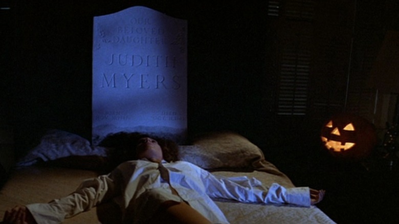 PJ Soles as Lynda in Hallowen, dead on the bed beneath a tombstone reading 'Our Beloved Daughter Judith Myers'