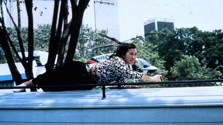 Michelle Yeoh as Jessica Yang laying on top of moving truck holding gun