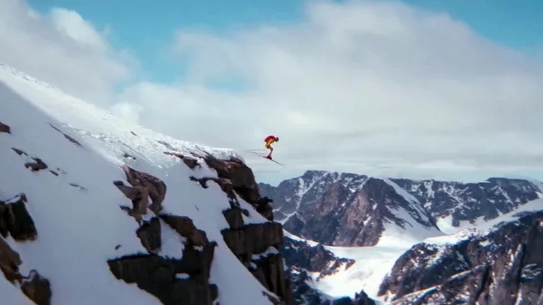 Wide shot of man (stuntman Rick Sylvester) in yellow snowsuit with red backpack skiing off a cliff in the mountains in The Spy Who Loved Me
