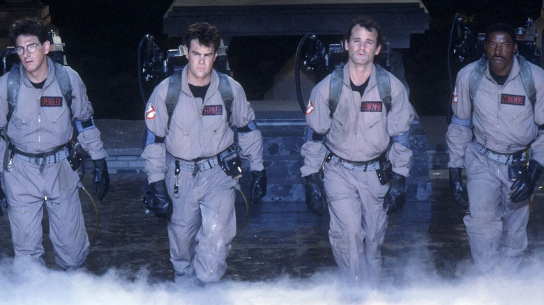 Harold Ramis as Egon Spengler, Dan Ackroyd as Ray Stantz, Bill Murray as Peter Venkman, and Ernie Hudson as Winston Zeddemore walking with their suits and proton packs on in Ghostbusters