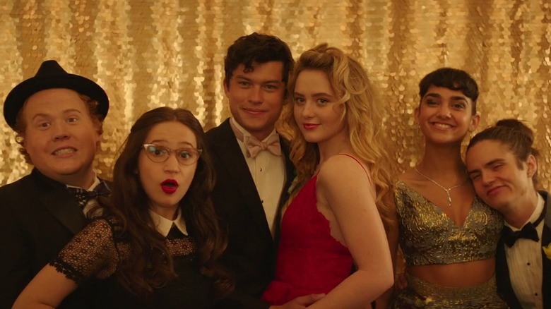 Jimmy Bellinger as Chad, Gideon Adlon as Sam, Graham Phillips as Austin, Kathryn Newton as Julie, Geraldine Viswanathan as Kayla, and Miles Robbins as Connor, posing for a prom photo in front of a sparkly gold curtain, in Blockers