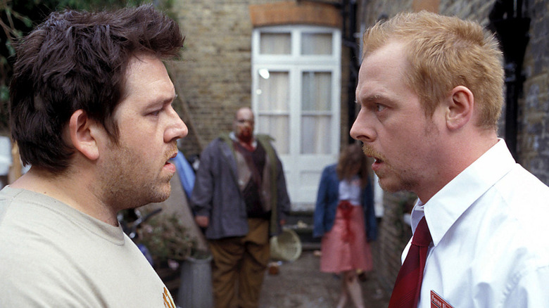 Ed (Nick Frost) and Shaun (Simon Pegg) face each other incredulously in front of two zombies in Shaun of the Dead