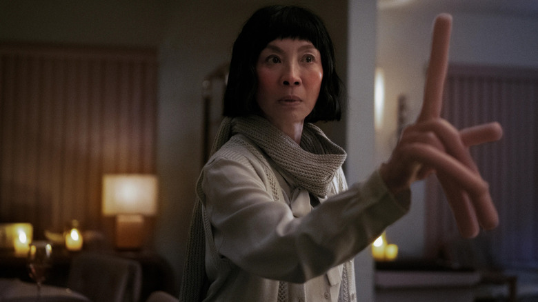 Michelle Yeoh as Evelyn, pointing a hot dog finger in Everything Everywhere All at Once