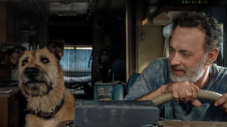 Tom Hanks as Finch, holding steering wheel and sitting next to dog in Finch