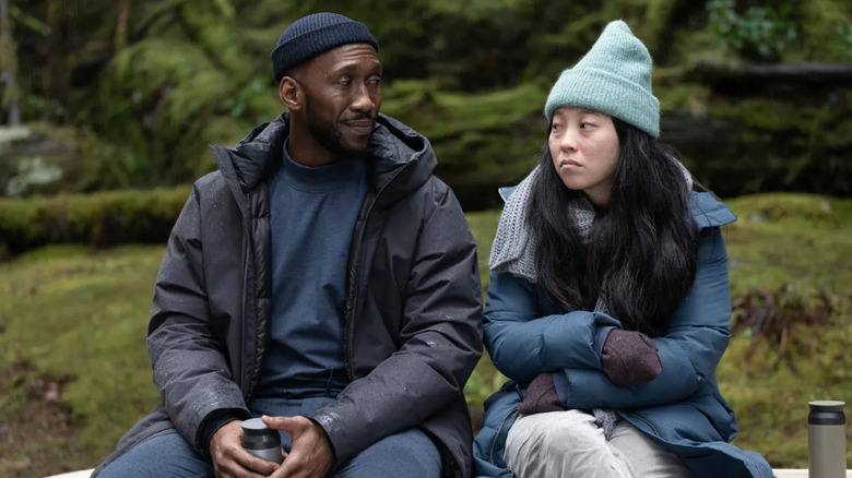 Mahershala Ali and Awkwafina sitting next to each other in coats in Swan Song