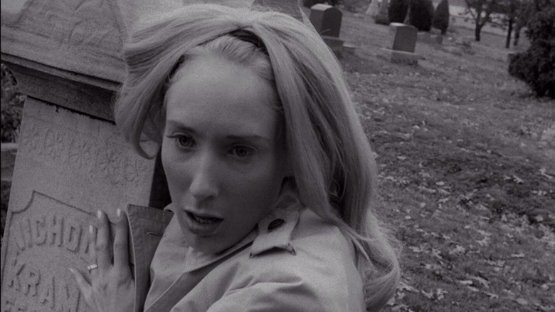 Judith O'Dea as Barbra, looking shocked while holding onto a tombstone in Night of the Living Dead.