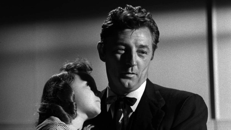 Robert Mitchum as Harry Powell with Sally Jane Bruce as Pearl Harper tucked on to his shoulder in The Night of the Hunter.
