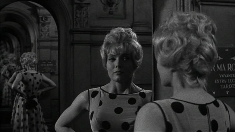 Corinne Marchand as Cléo wearing polka dot dress and looking into the mirror in Cléo from 5 to 7