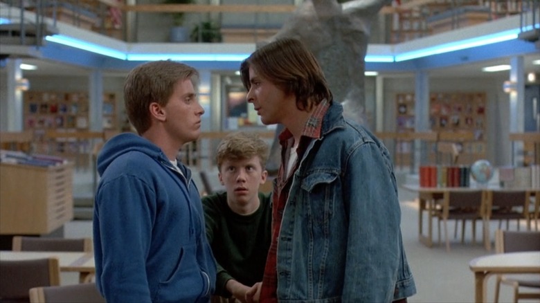 Emilio Estevez as Andrew, Anthony Michael Hall as Brian, and Judd Nelson as Bender, staring each other down in the library in The Breakfast Club