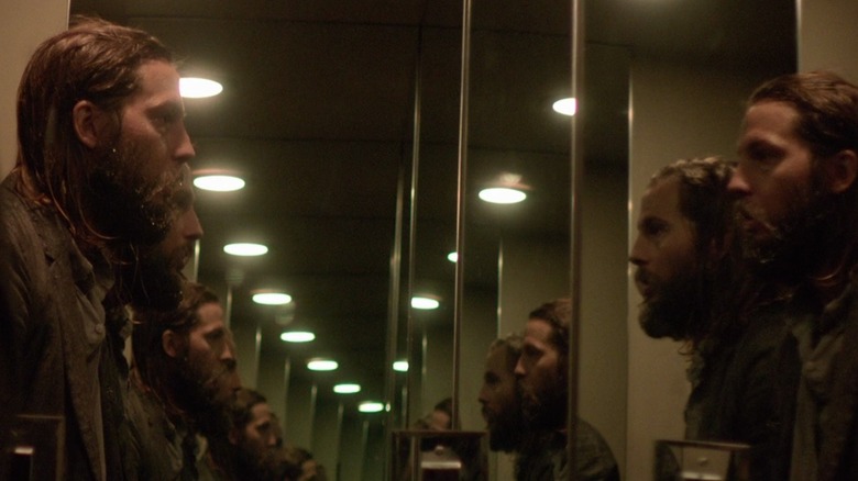 Logan Marshall-Green staring at himself in a mirror reflected many times, in The Invitation