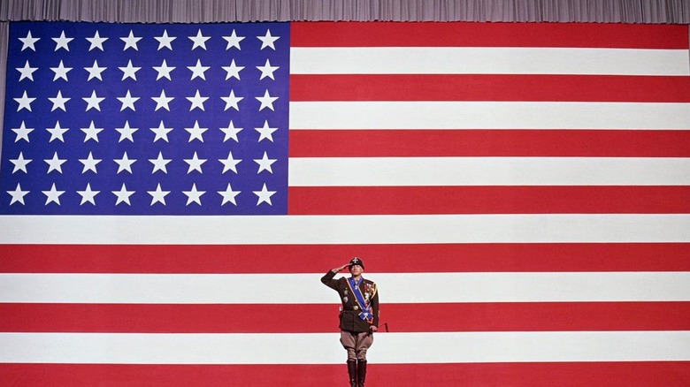 General Patton (George C. Scott) speaks in front of a flag in Patton