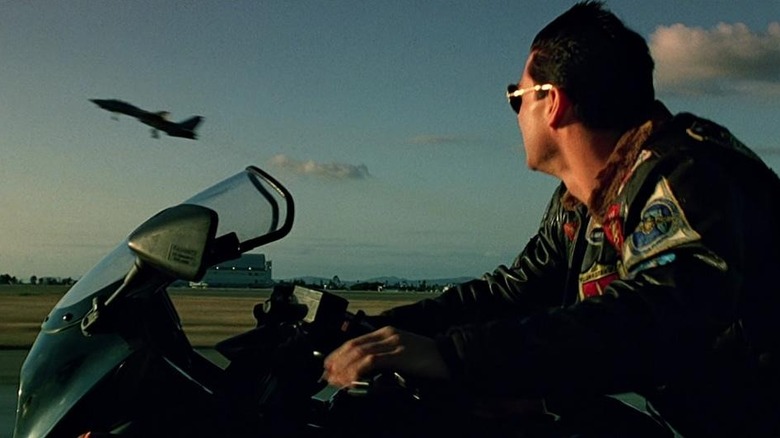 Maverick (Tom Cruise) watches a fighter jet from his bike in Top Gun