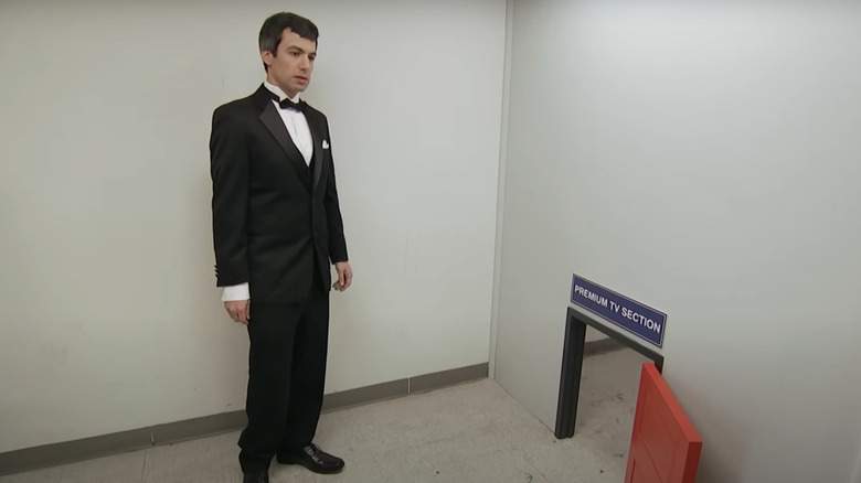 Nathan Fielder wearing a tuxedo in a room with a small door in Nathan For You