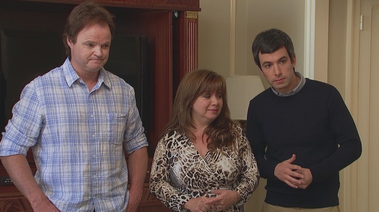 Nathan Fielder standing in a hotel room with two parents in Nathan For You