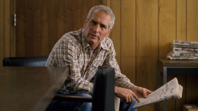 Paul Newman points to a newspaper