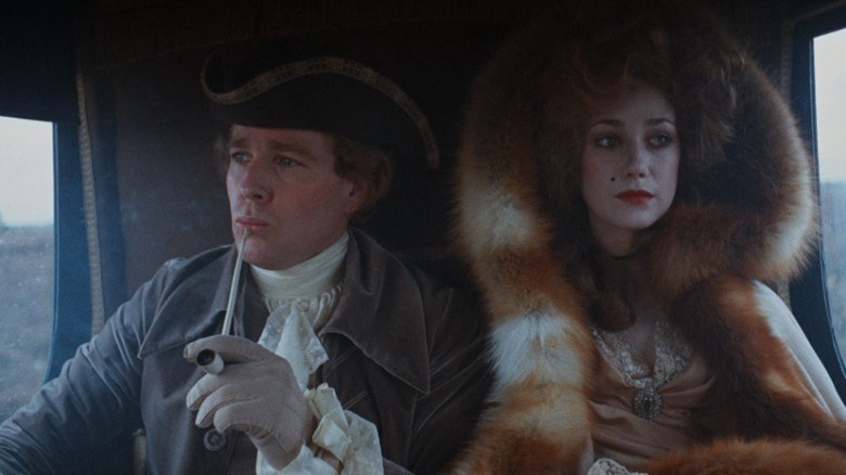 Ryan O'Neal as Barry Lyndon smoking a pipe next to Marisa Berenson as Lady Honoria Lyndon in the backseat of a carriage in Barry Lyndon
