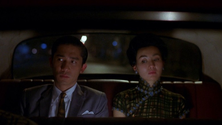 Tony Leung Chiu-wai as Chow Mo-wan and Maggie Cheung as Su Li-zhen sitting in the backseat of a car in In the Mood for Love