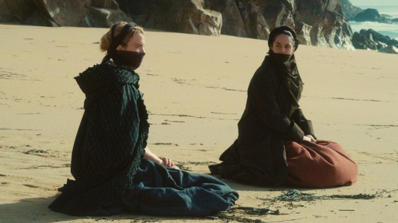 Adèle Haenel as Héloise and Noémie Merlant as Marianne sitting on a beach in Portrait of a Lady on Fire